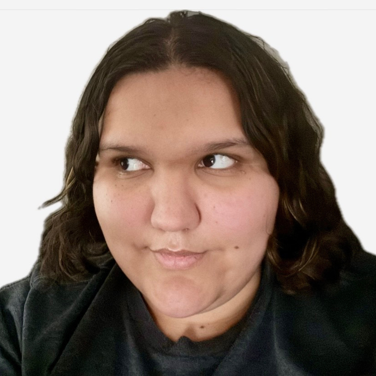 Kaitlynn, a young woman with brown hair, smiles and poses for a selfie-style photograph. Kaitlynn has dark brown hair and is wearing grey t-shirt.